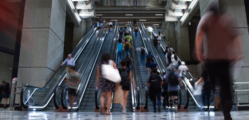 Foto de varias personas subiendo y bajando por las escaleras mecánicas en una estación del metro de Santiago.