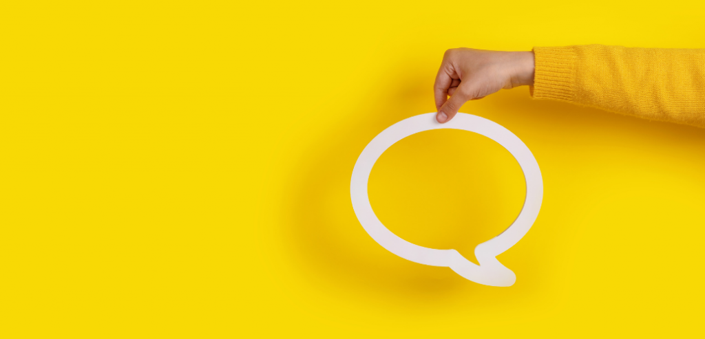 Imagen que muestra una mano sosteniendo un globo de diálogo, sobre un fondo amarillo