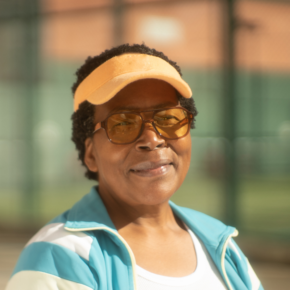 Foto de una mujer mayor con ropa deportiva, visera y gafas para el sol.