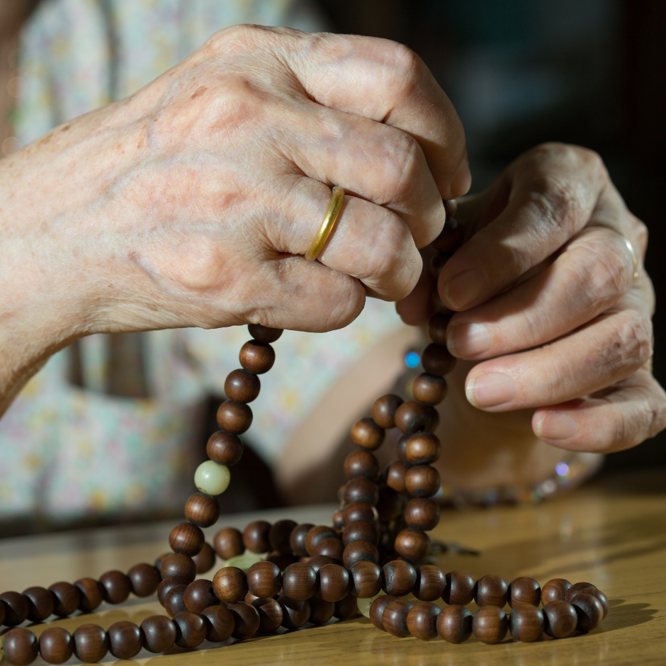 Foto de las manos de una persona mayor sosteniendo un rosario.