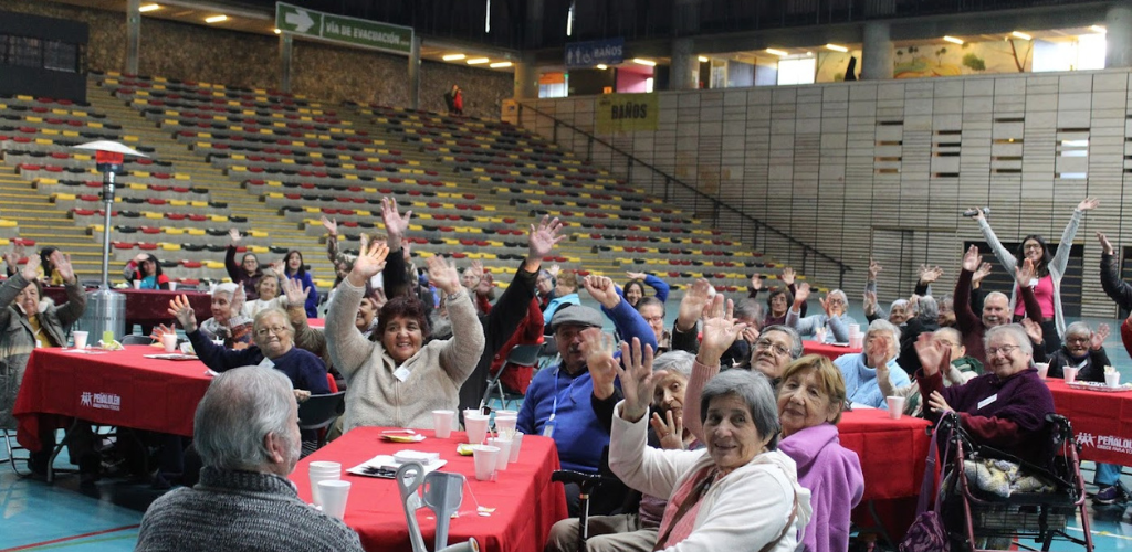 Asistentes del evento Mayor y Mejor en la comuna de Peñalolén saludan a la cámara con los brazos en alto