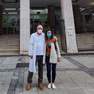 Foto de dos personas de pie sonriendo frente a un edificio.