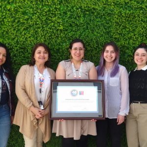 Foto de 5 mujeres de pie y sonriendo. La persona del medio sostiene un cuadro con una certificación del sello 40 horas.