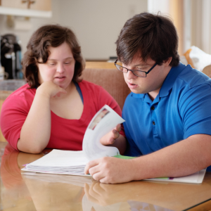 Foto de una mujer y un hombre jóvenes con discapacidad intelectual leyendo un libro