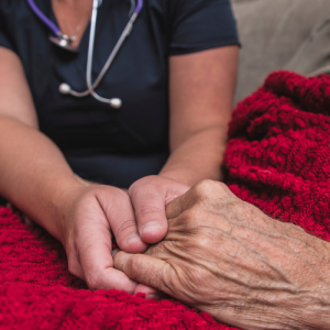 Foto de una enfermera tomándole la mano a una persona mayor.