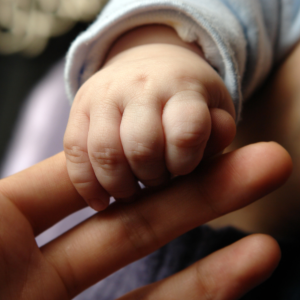 Foto de la mano de un bebé tomando el dedo de la mano de una persona adulta.
