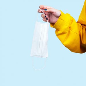 Foto que muestra la mano de una persona joven sosteniendo una mascarilla