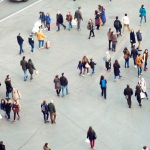 Fotografía aérea de muchas personas distintas caminando en distintas direcciones por una calle peatonal.