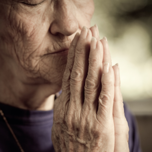 Foto de una mujer mayor rezando.