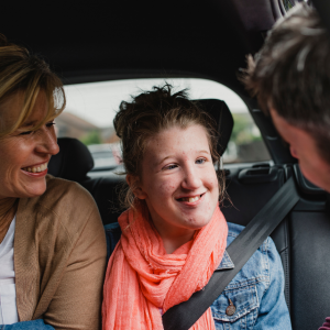 Foto de una adolescente con discapacidad intelectual en un auto junto a sus dos padres.