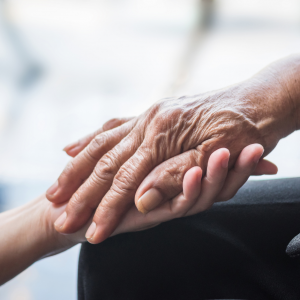 Foto que muestra la mano de una persona mayor sobre la palma de la mano de una persona más joven