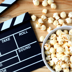 Foto de una claqueta de películas y un pocillo con cabritas sobre una mesa