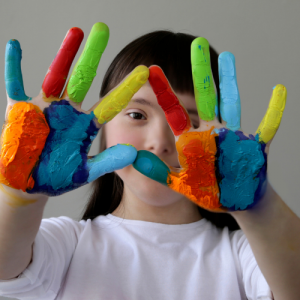 Girl with down syndrome showing her hands with different colour paintings