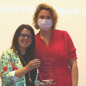 Foto de Marcela Tenorio recibiendo el premio de Compromiso UAndes junto a una mujer que se lo entrega.