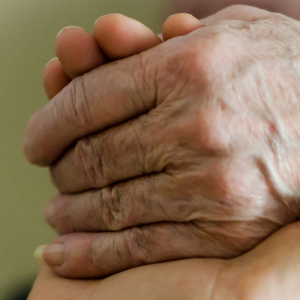 Foto de la mano de una persona mayor tomando la mano de una persona más joven